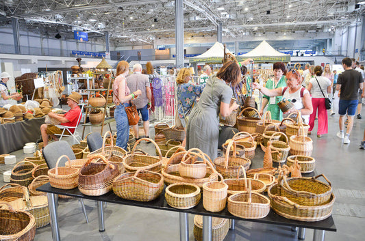 Lithuanian basket sales booth at the World Wicker and Weaving Festival, filled with handwoven baskets and lively browsing visitors / 世界かご編み大会のリトアニア販売ブース。手編みのかごが並び、来場者で賑わう様子