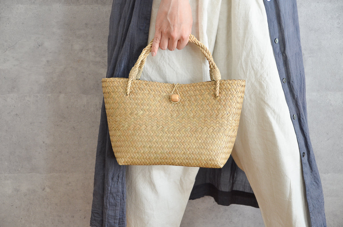 Krajood grass mini bag with closure held in hand / カチューの留め具付きミニバッグを手に持った様子