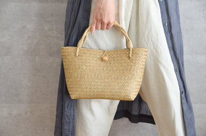 Krajood grass mini bag with closure held in hand / カチューの留め具付きミニバッグを手に持った様子