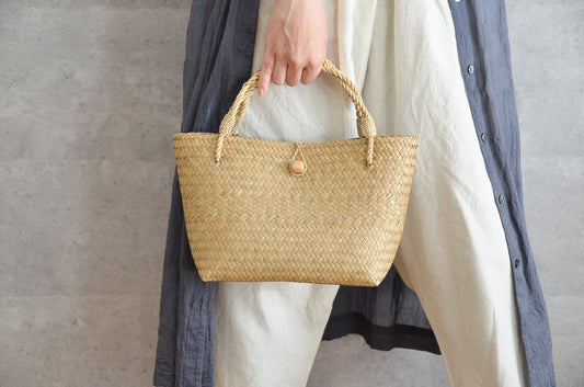 Krajood grass mini bag with closure held in hand / カチューの留め具付きミニバッグを手に持った様子