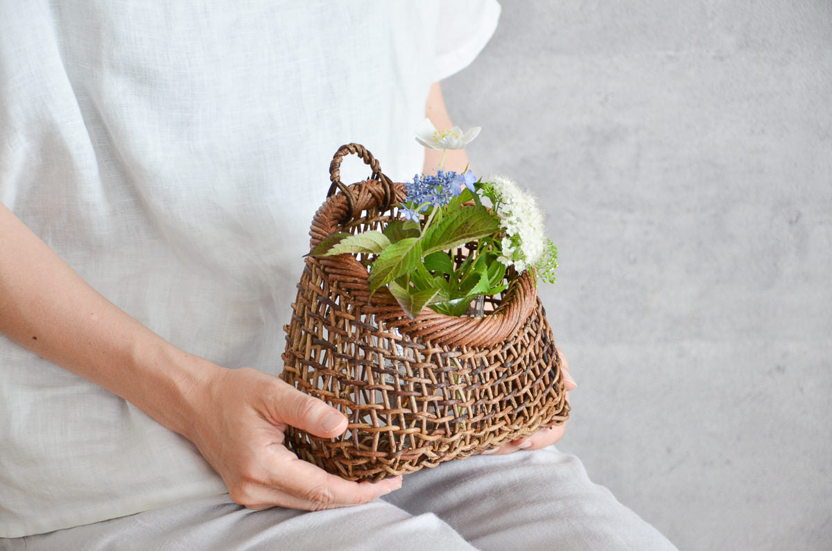 Akebi flower basket with sukashi weave held on lap / 花を生けたあけびのすかし編み花かごを持っている様子