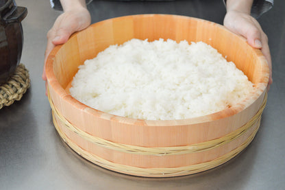 Sawara cypress rice tub with bamboo hoop and cooked rice / さわらの飯台（竹タガ付）にご飯が入り、手が添えられた様子