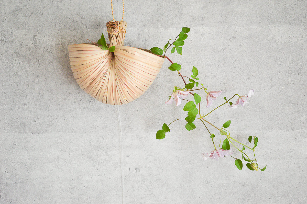 Nypa palm scoop hung on a wall with flowers / ニッパヤシのすくいを壁に掛けて花を生けた様子