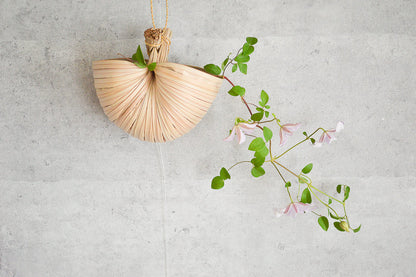 Nypa palm scoop hung on a wall with flowers / ニッパヤシのすくいを壁に掛けて花を生けた様子