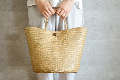 Krajood grass double-weave storage bag held in hand / カチューの二重編みストレージバッグを手に持った様子