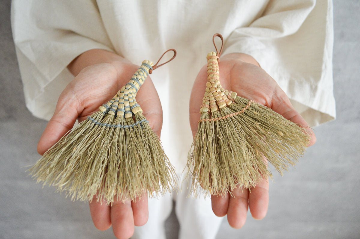 Broomcorn ginkgo-shaped small brooms placed on both hands / ホウキモロコシのいちょう型小箒を両手にのせた様子