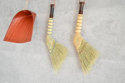 Broomcorn feather-shaped small brooms hanging on a wall / ホウキモロコシの羽根型小箒を壁に掛けた様子