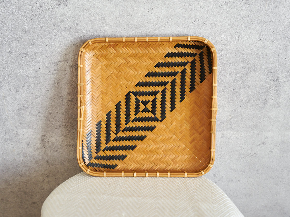 Square carbonized bamboo plate with a black geometric pattern, leaning against a wall / 黒い幾何学模様のある炭化竹の角皿を壁に立てかけた様子