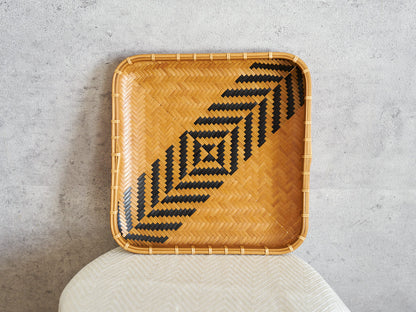 Square carbonized bamboo plate with a black geometric pattern, leaning against a wall / 黒い幾何学模様のある炭化竹の角皿を壁に立てかけた様子