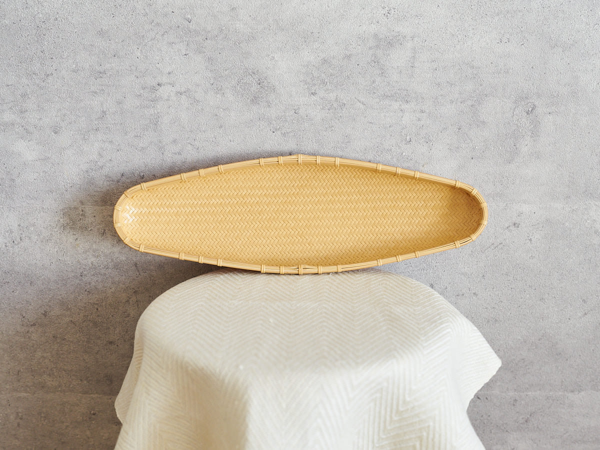 Slim oval white bamboo plate leaning against a wall / 白竹の細長い楕円皿を壁に立てかけた様子