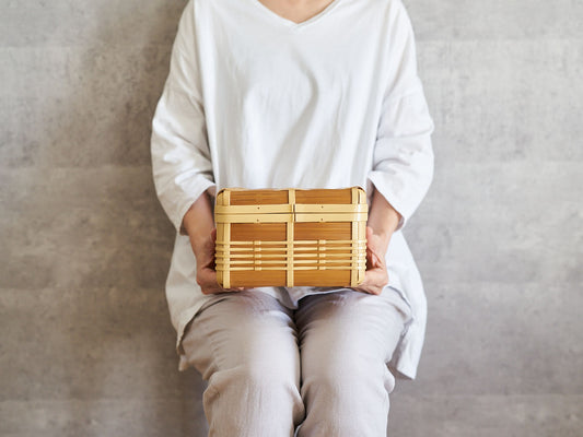 Holding the small, shallow lidded basket “Kiritto” made of white and carbonized bamboo / 白竹と炭化竹の蓋つきかご「kiritto」小・浅を持っている様子