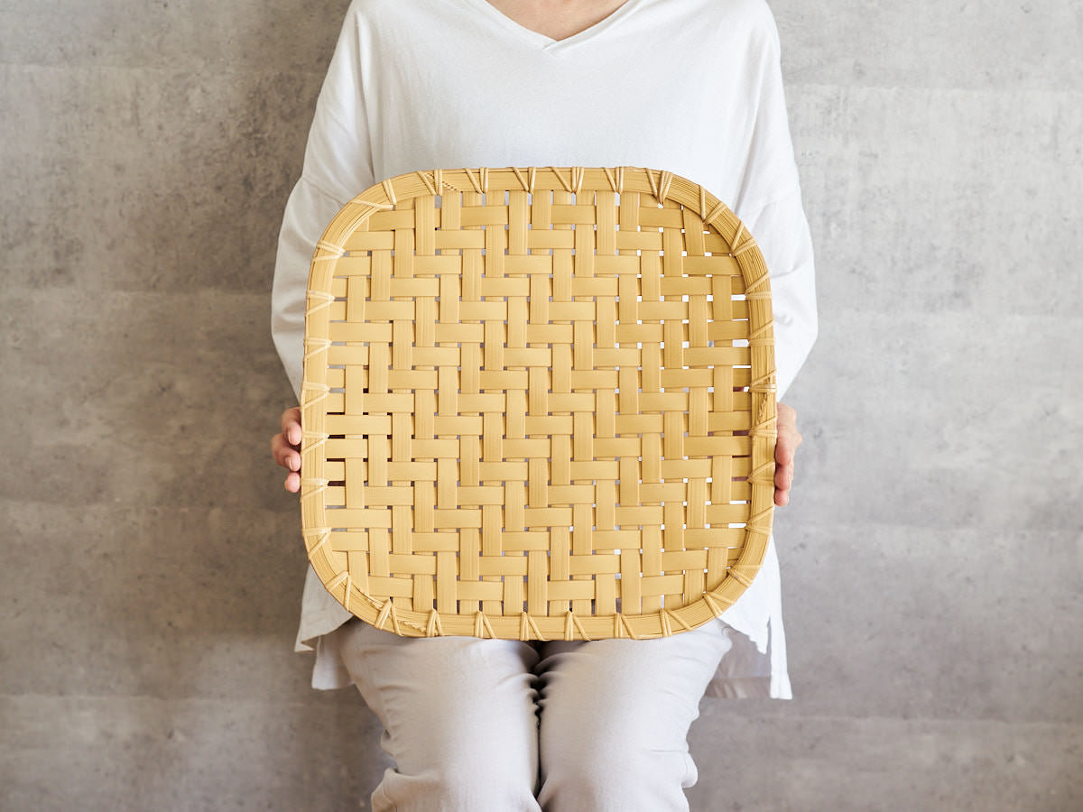 Medium-sized white bamboo plate held upright / 白竹の中皿を立てて持っている様子