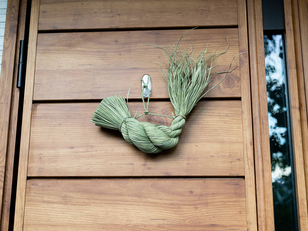 Rice straw shimekazari lucky twist on a wooden door / 稲わらのしめかざり（福縄）が木の扉に掛けられている様子