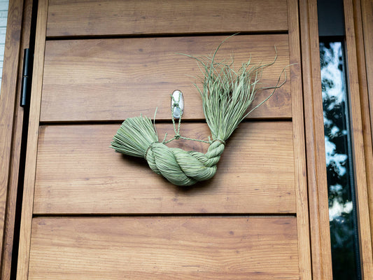 Rice straw shimekazari lucky twist on a wooden door / 稲わらのしめかざり（福縄）が木の扉に掛けられている様子