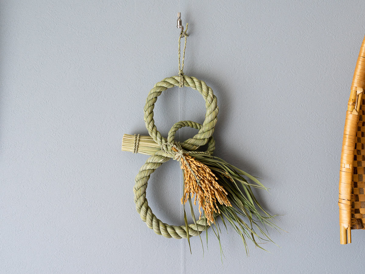 Rice straw shimekazari with three rings hanging on a wall / 稲わらのしめかざり（三拍子）が壁に掛けられている様子