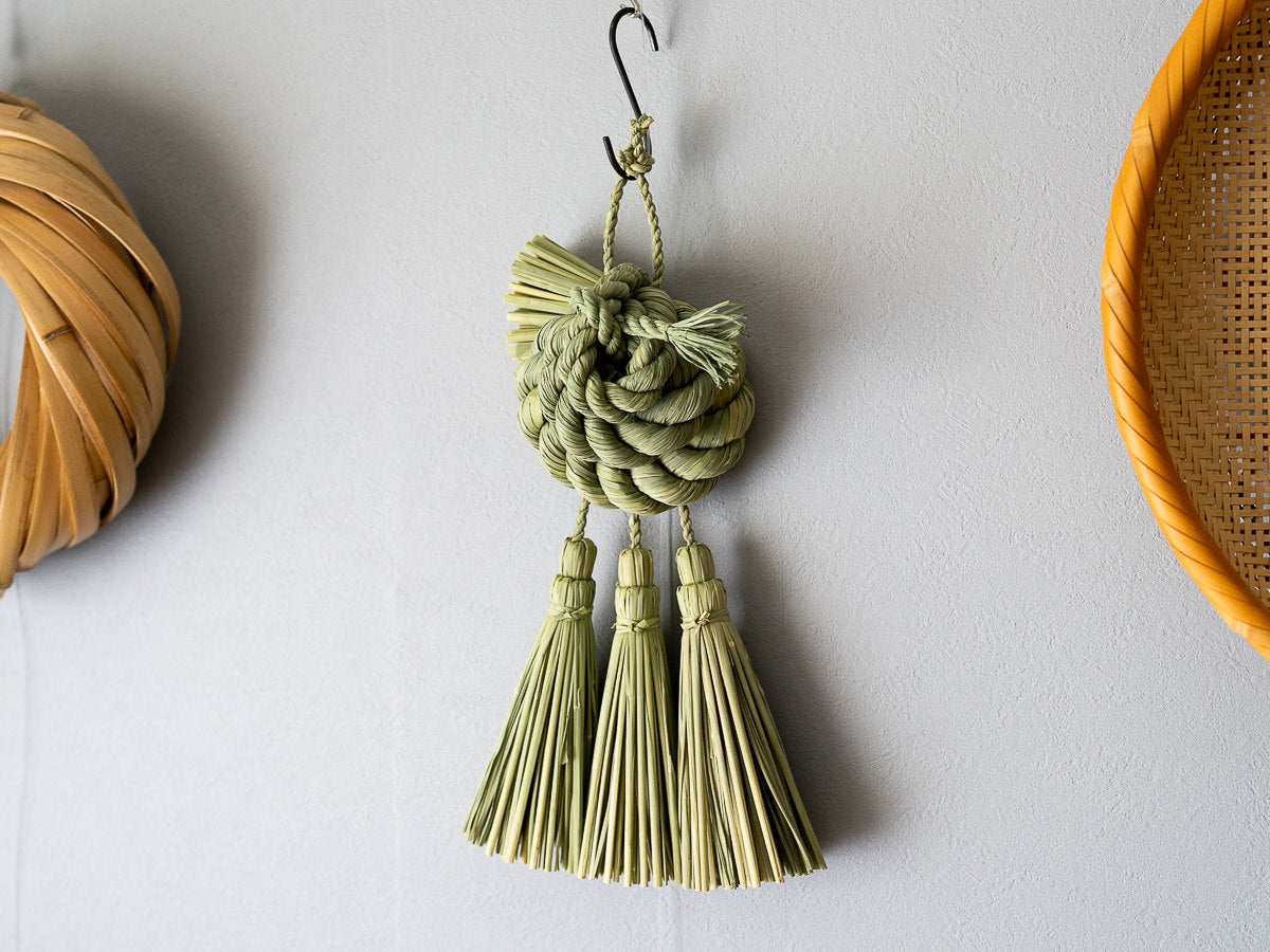 Rice straw shimekazari with spiral knot hanging on a wall / 稲わらのしめかざり（巡り廻る）が壁に掛けられている様子