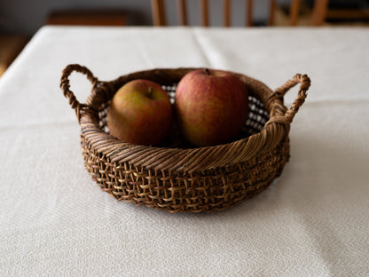Akebi round basket with sukashi weave on a table / りんごが入ったあけびのすかし編み丸かごがテーブルに置かれている様子