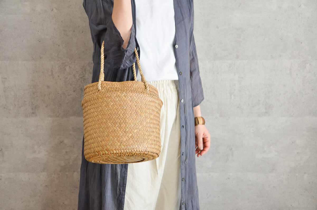 Krajood grass round double-weave handbag held in hand / カチューの丸型二重編み手提げかごを手に持った様子