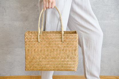 Hand holding a Krajood grass attaché-style basket bag / カチューのアタッシュ型かごバッグを手に持った様子