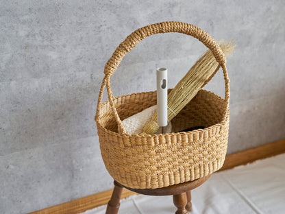 Water hyacinth oval gondola basket with triple braid holding cleaning tools placed on a stool / 掃除道具を入れたウォーターヒヤシンスの三つ編み入りオーバルゴンドラバスケットをスツールの上に置いた様子