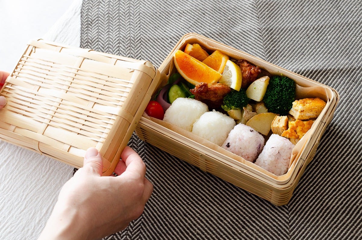 White bamboo lunch box with lid open / 中身の入った白竹の弁当箱を開けた様子