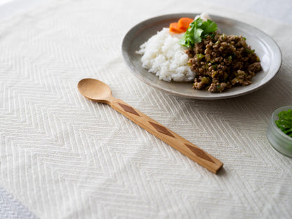 Smoked bamboo spoon with diamond pattern on a tablecloth / ダイヤ模様のある炭竹のスプーンをテーブルクロスの上に置いた様子