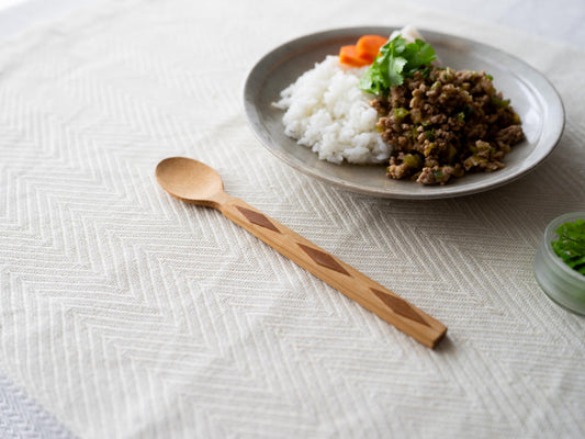 Smoked bamboo spoon with diamond pattern on a tablecloth / ダイヤ模様のある炭竹のスプーンをテーブルクロスの上に置いた様子