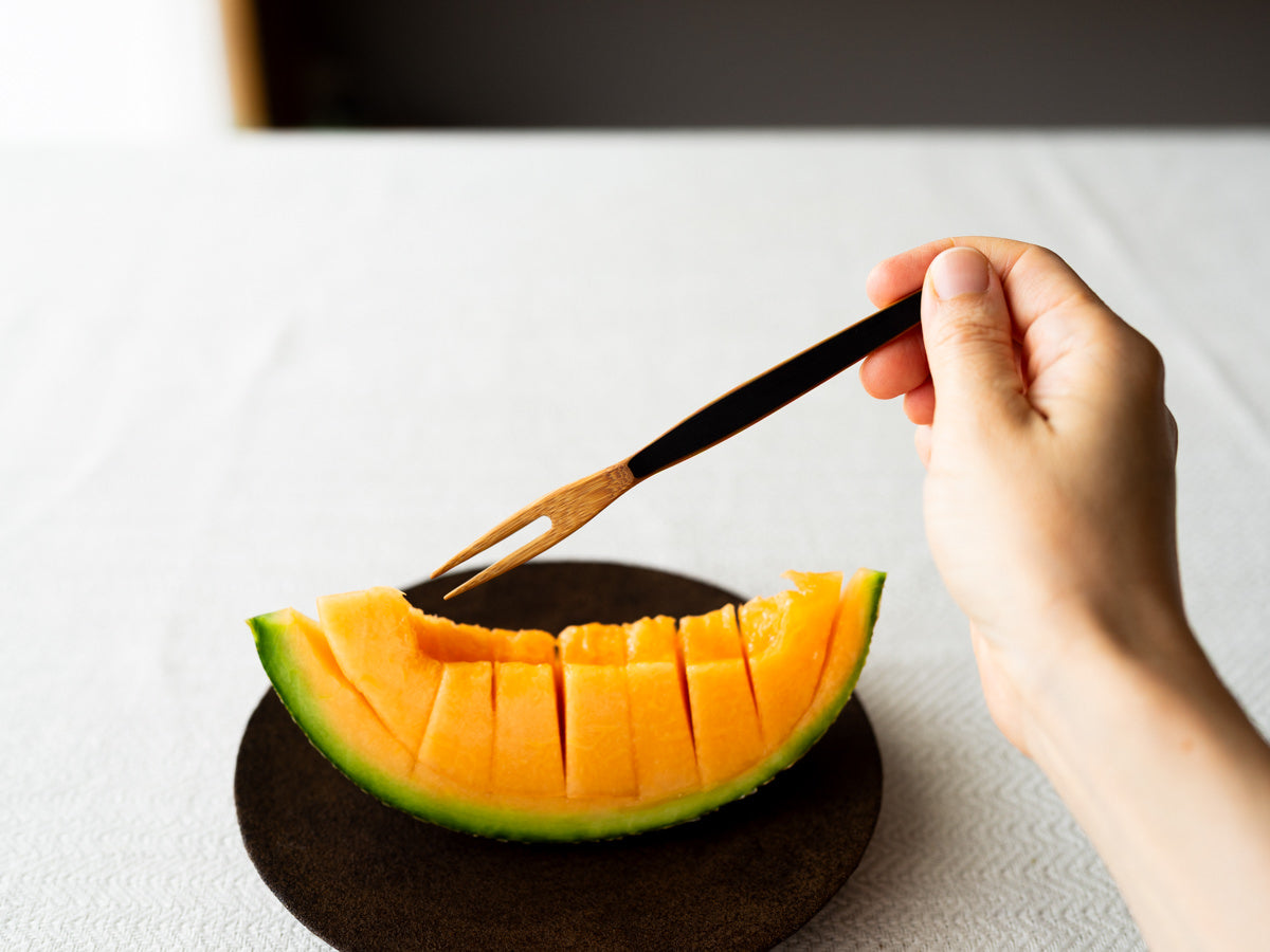 Smoked bamboo fruit fork held in hand / 炭竹のフルーツフォークを手に持っている様子