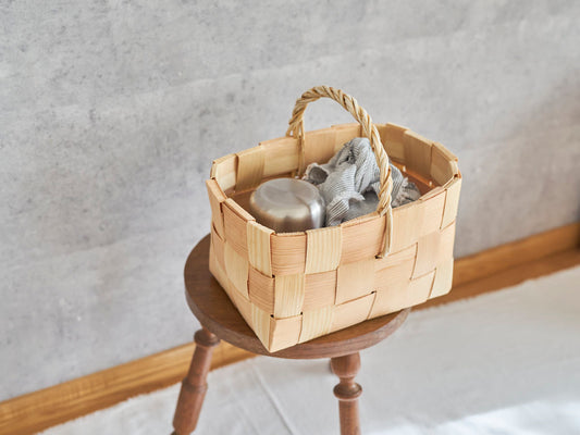 Pine shopping basket with one handle holding a lunch placed on a stool / お弁当を入れたパインのワンハンドルショッピングバスケットをスツールの上に置いた様子