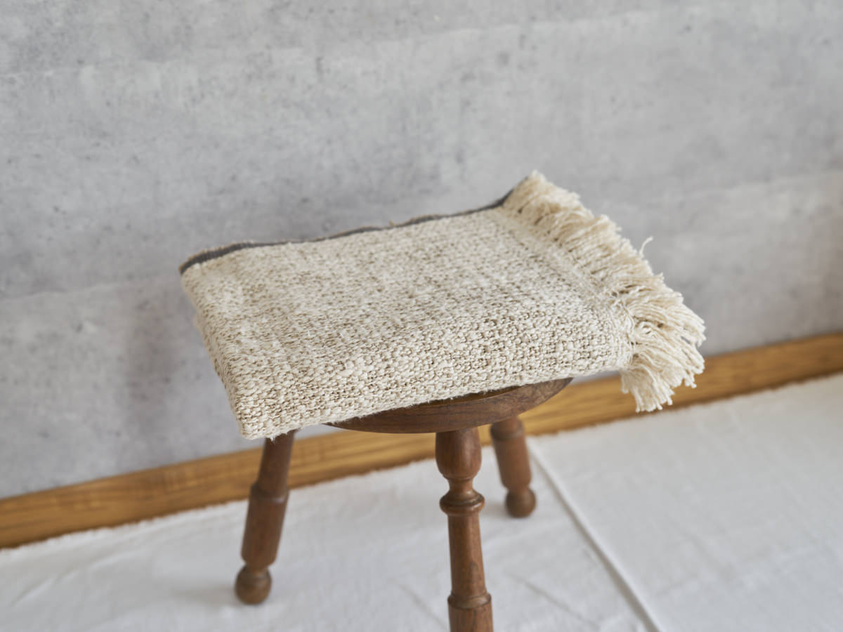 Woven cotton stole placed on a wooden stool / コットンのガラ紡ストールをスツールに置いた様子