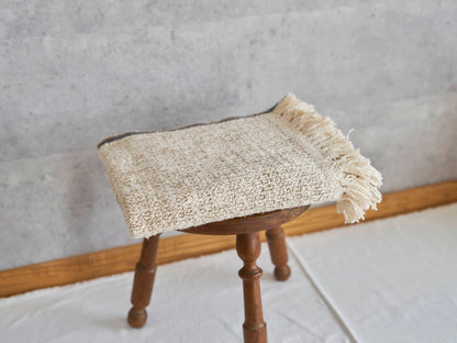 Woven cotton stole placed on a wooden stool / コットンのガラ紡ストールをスツールに置いた様子