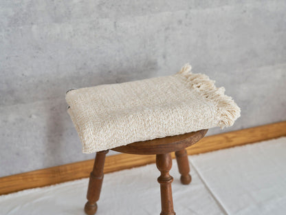 Woven cotton stole placed on a wooden stool / コットンのガラ紡ストールをスツールに置いた様子