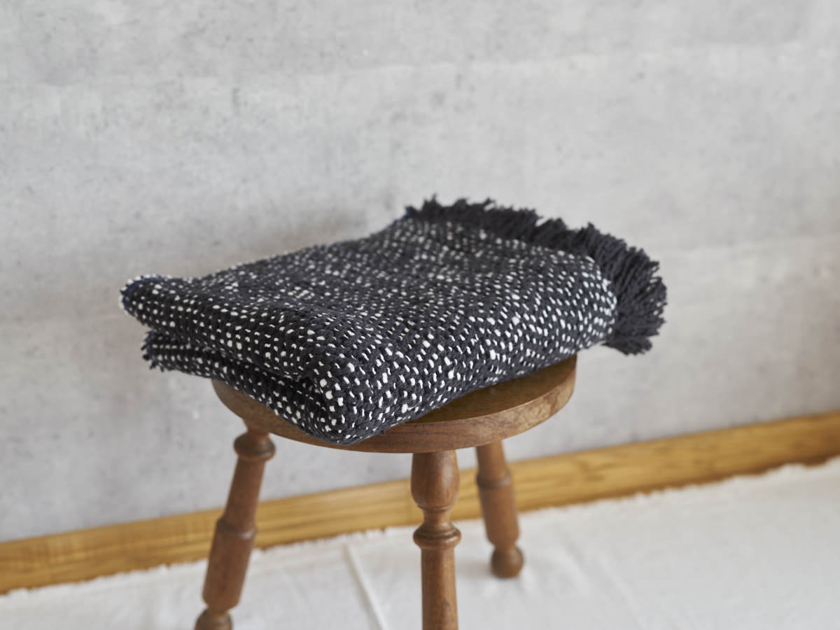 Woven cotton stole placed on a wooden stool / コットンのガラ紡ストールをスツールに置いた様子
