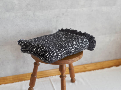 Woven cotton stole placed on a wooden stool / コットンのガラ紡ストールをスツールに置いた様子