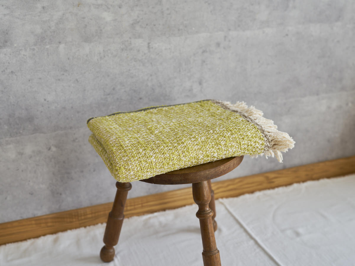 Woven cotton stole placed on a wooden stool / コットンのガラ紡ストールをスツールに置いた様子