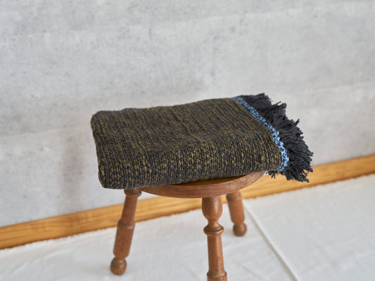 Woven cotton stole placed on a wooden stool / コットンのガラ紡ストールをスツールに置いた様子