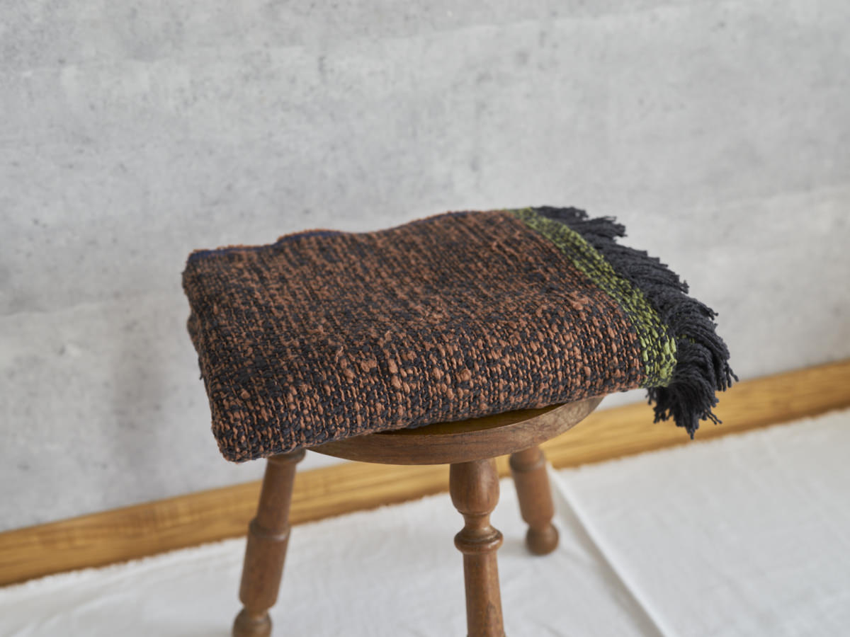 Woven cotton stole placed on a wooden stool / コットンのガラ紡ストールをスツールに置いた様子