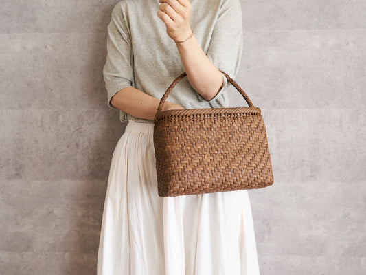 A person holding a one-handle grapevine basket bag with a braided handle / やまぶどうの編組み手ワンハンドル手提げを持っている様子