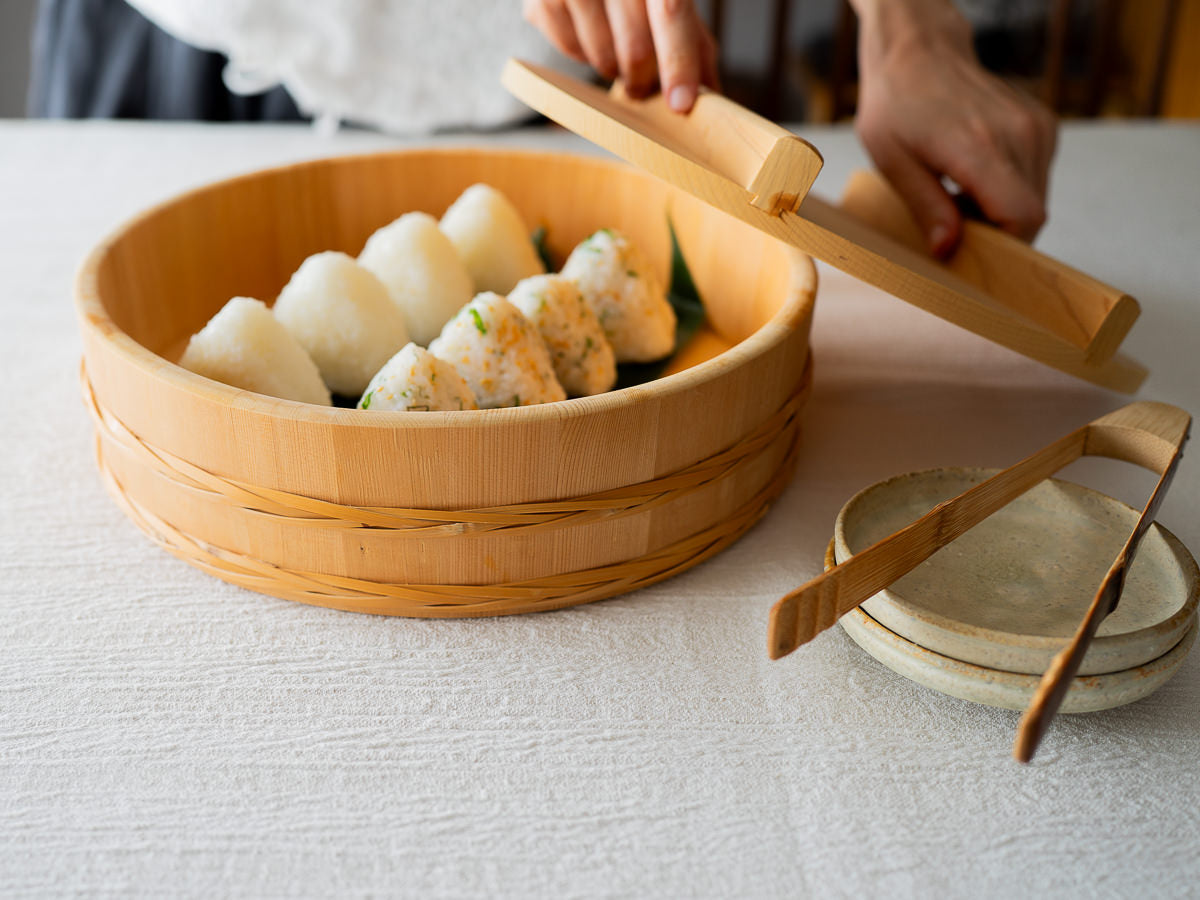Sawara cypress rice tub with bamboo hoop holding onigiri / さわらの飯台（竹タガ付）におにぎりを入れた様子