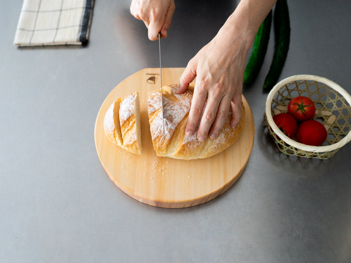 Hinoki round cutting board with bread being cut / ひのきの丸まな板でパンを切っている様子