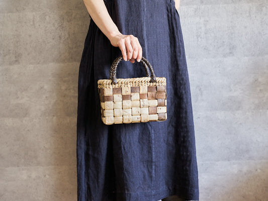 Hand holding a small walnut bark basket with checker weave / 小ぶりなくるみの市松編み手提かごを手に持った様子