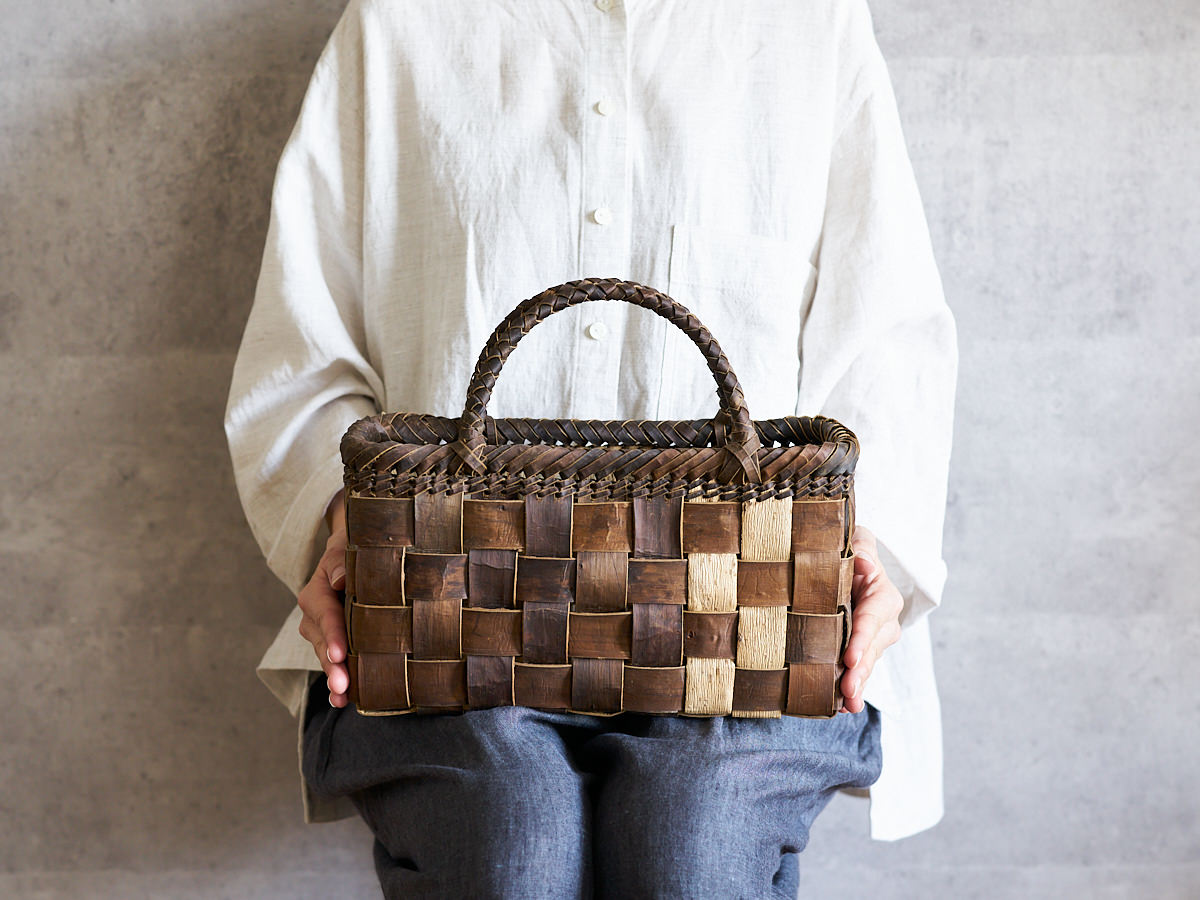 Hand holding a walnut bark basket with checker weave / くるみの市松編み手提かごを手に持った様子