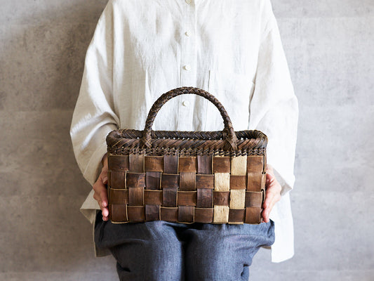 Hand holding a walnut bark basket with checker weave / くるみの市松編み手提かごを手に持った様子