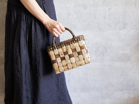 Hand holding a small walnut bark basket with checker weave / くるみの市松編み手提かごを手に持った様子