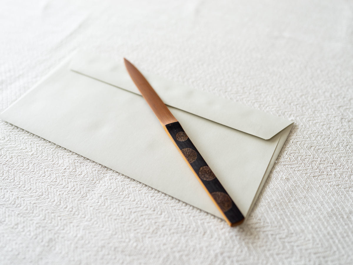 Smoked bamboo letter opener on an envelope / 炭竹のペーパーナイフが封筒の上に置かれている様子