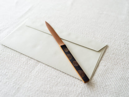 Smoked bamboo letter opener on an envelope / 炭竹のペーパーナイフが封筒の上に置かれている様子