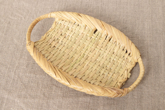 Small oval bamboo tray with handles on fabric background / 両口付きの竹ざるを布の上に置いた様子