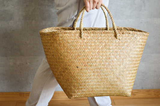 Krajood grass square-bottom handbag held in hand / カチューの底角の手提げかごを手に持った様子