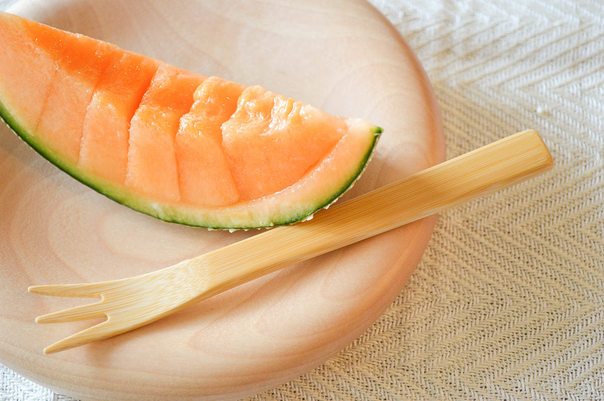 Moso bamboo dessert fork beside fruit on plate / 孟宗竹のデザートフォークをフルーツに添えた様子